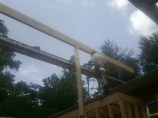 Carpenter setting a ridge beam over a new addition frame — Ice Dam Removal by Roofing Brothers in Alva