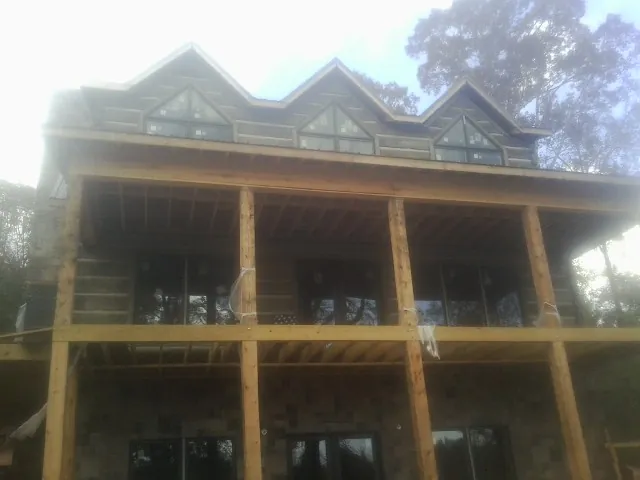 Dormers and porch framing on a large log home under construction — Roof Coating work by our crew in Alva